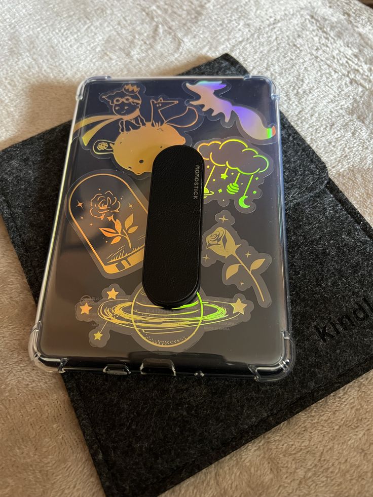 an electronic device sitting on top of a black cloth covered case with cartoon images and symbols