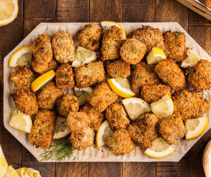 a platter filled with lemon and chicken nuggies on top of a wooden table