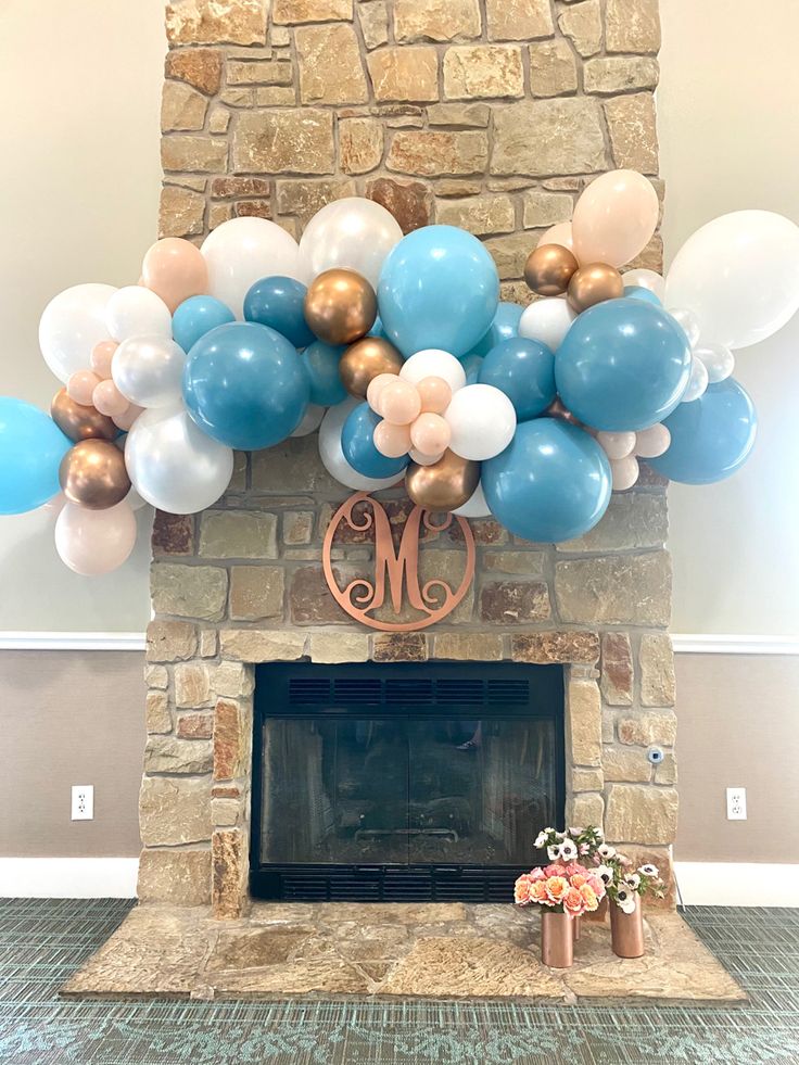 a fireplace decorated with balloons and a monogrammed mantel