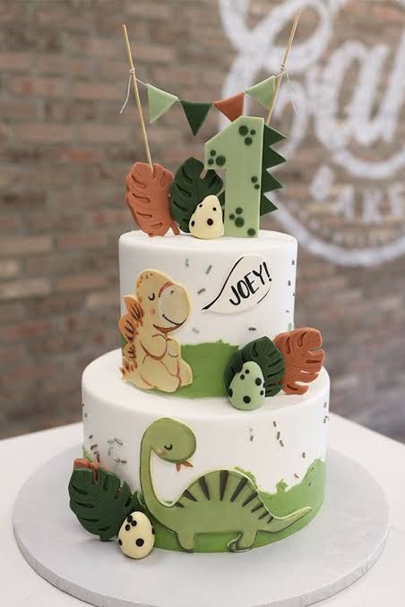 a three tiered cake decorated with dinosaurs