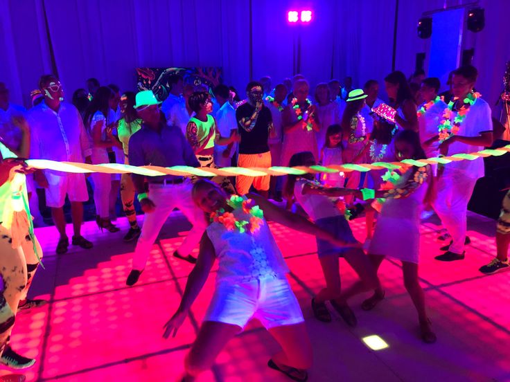 a group of people standing on top of a dance floor with neon colored lights around them