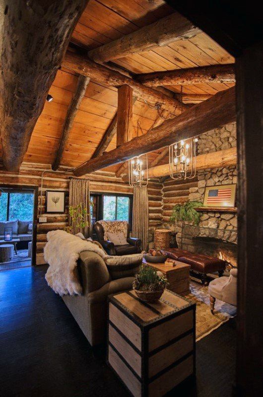 a living room filled with furniture and a fire place next to a stone wall covered in logs