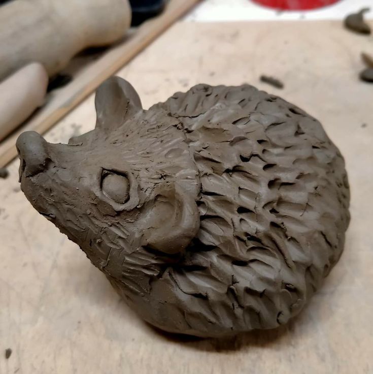 a clay animal head sitting on top of a wooden table next to other tools and materials