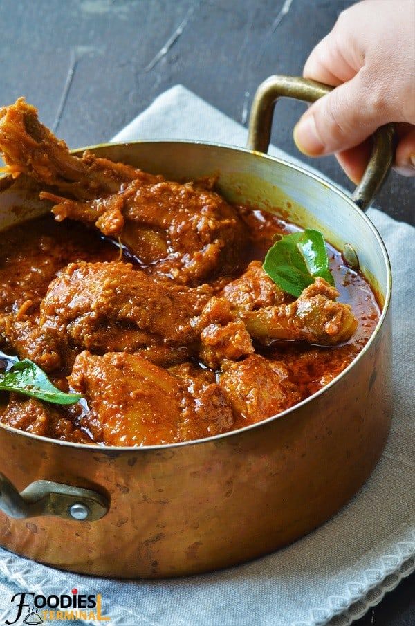 a person holding a spoon in a pot filled with meat and sauce on top of a napkin