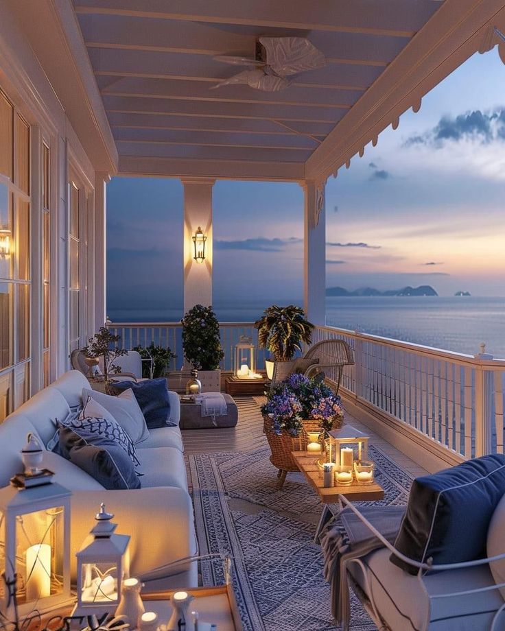 an outdoor living area with wicker furniture and candles lit on the balcony overlooking the ocean