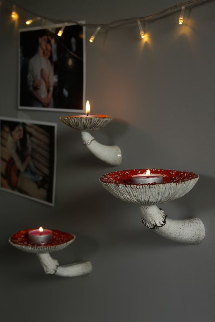 two white birds holding red plates with lit candles