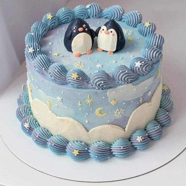 there is a cake with two penguins on top and blue icing around the edges