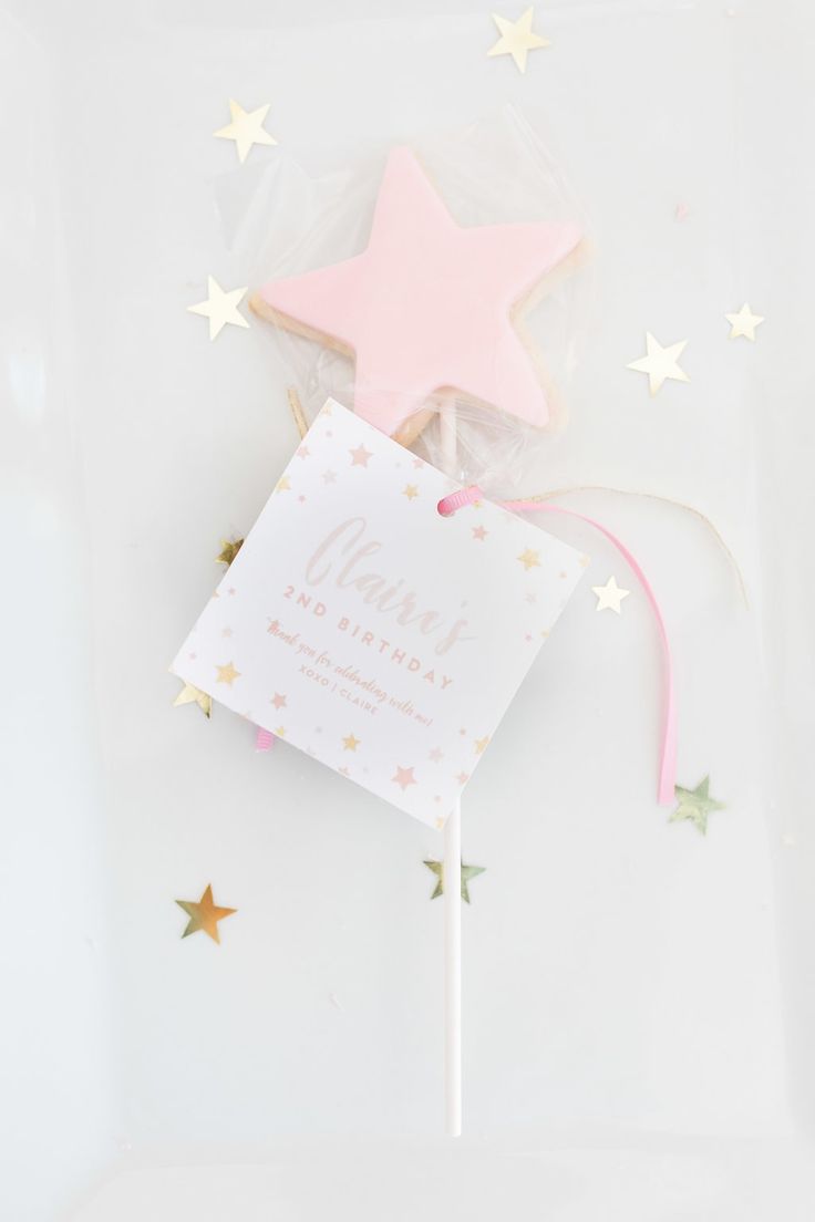 a pink and gold star shaped cake topper on a white plate with stars around it