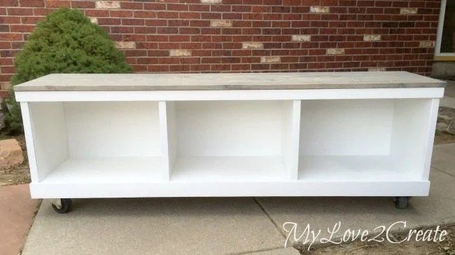 a white shelf sitting on top of a sidewalk next to a brick wall and grass