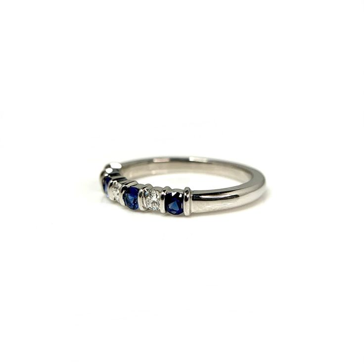 a white gold ring with three blue stones on the side and two diamonds in the middle