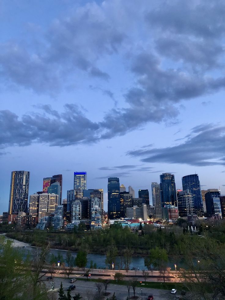 the city skyline is lit up at night, with clouds in the sky above it