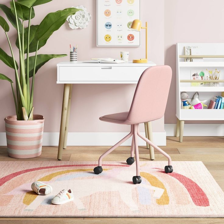 a pink chair sitting on top of a rug next to a desk