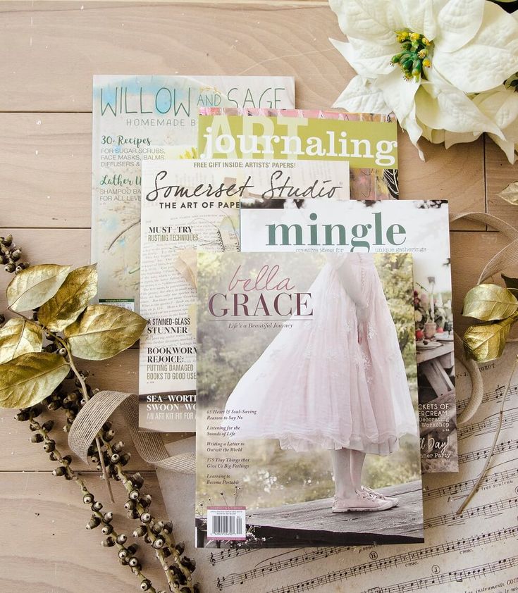 magazines and flowers on a wooden surface with gold leafy garlands, beads, and pearls