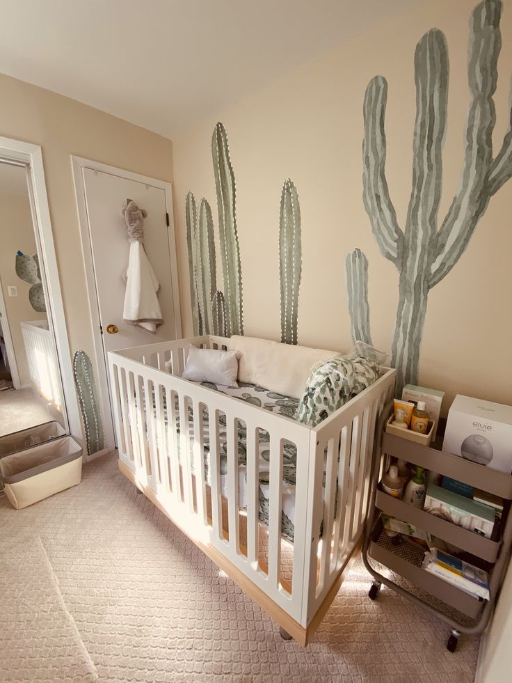 a baby's room with a cactus mural on the wall and a crib