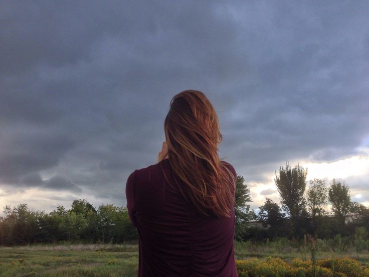 a woman is flying a kite on a cloudy day