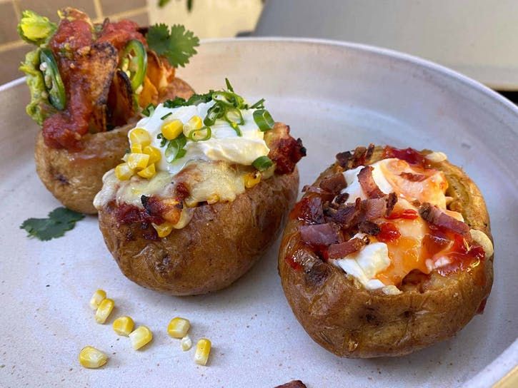 three baked potatoes with toppings on a plate