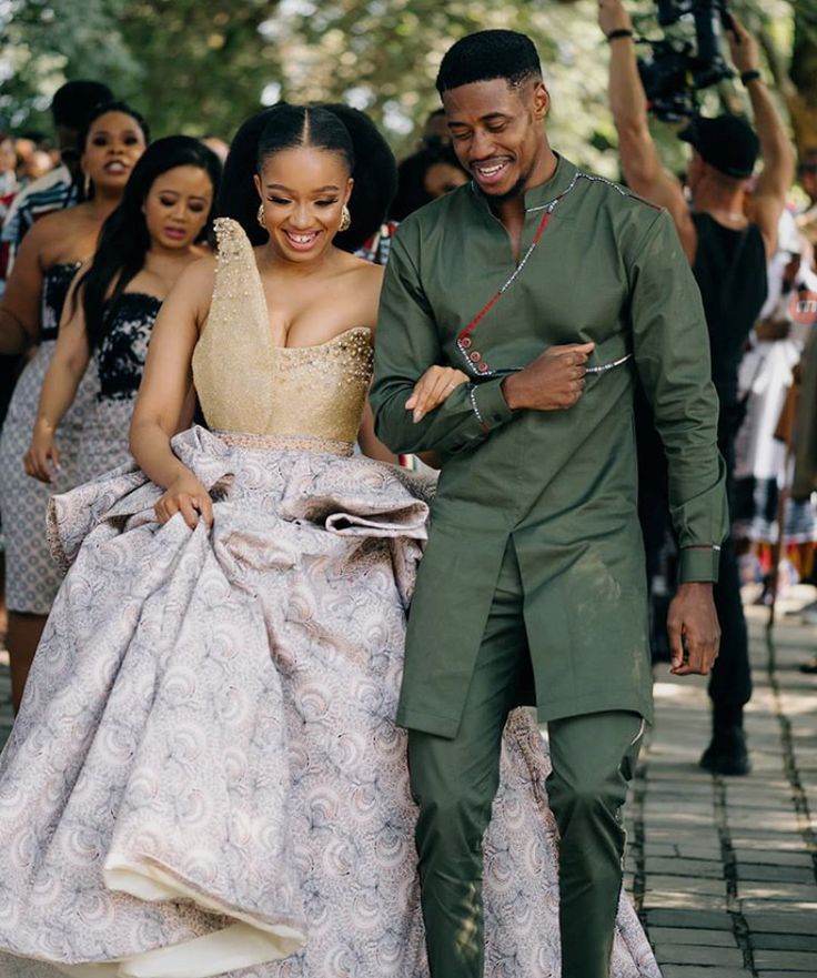 a man and woman are walking down the street in formal attire with cameras around them