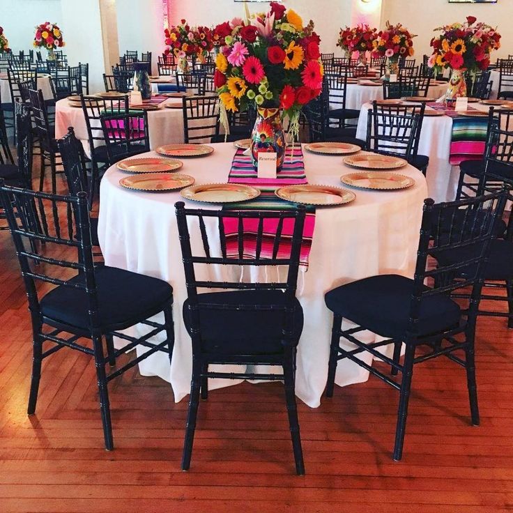 the tables are set with white tablecloths and black chairs