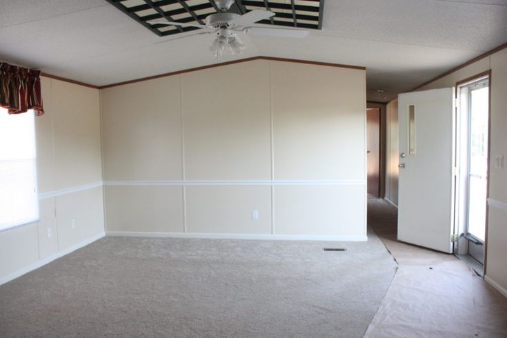 an empty room with white walls and carpeting in the foreground is a ceiling fan