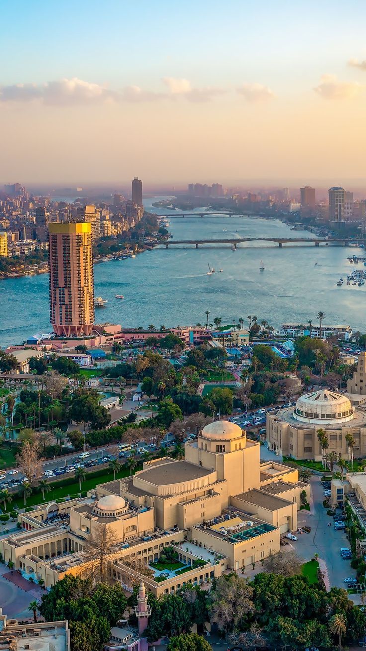 an aerial view of a large city with water and buildings in the background at sunset