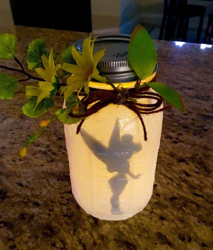 a mason jar with leaves and a shadow on the lid sitting on a counter top