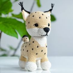 a small crocheted dog sitting next to a potted plant