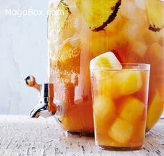 a pitcher and glass filled with liquid sitting next to each other on top of a table