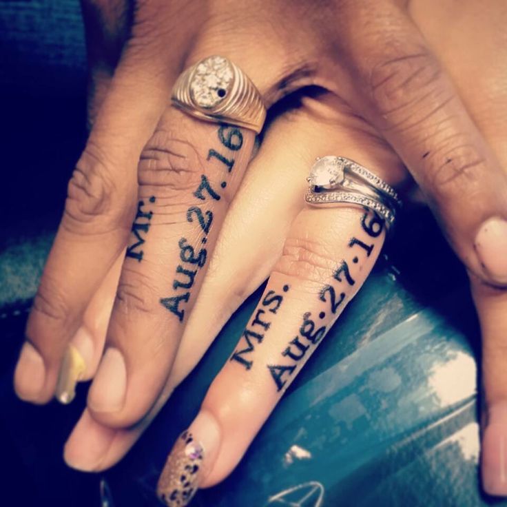 two people holding hands with tattoos on their fingers