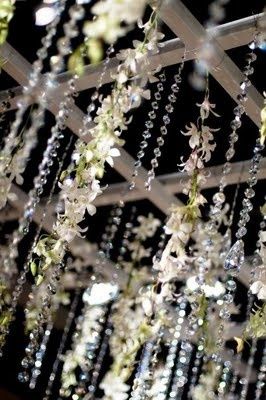 the chandelier is decorated with white flowers and pearls hanging from it's ceiling