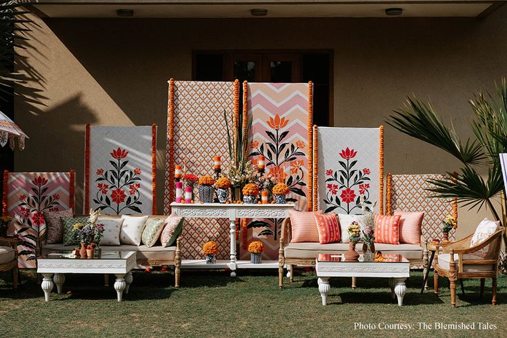 an outdoor area with couches, tables and chairs covered in colorful wall hangings