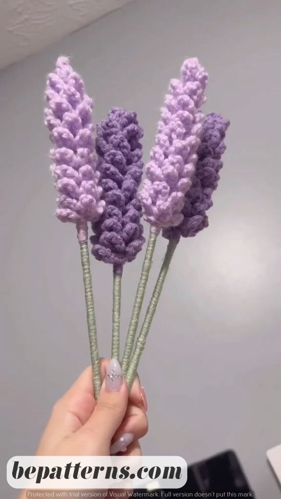 three crocheted lavender flowers are being held up