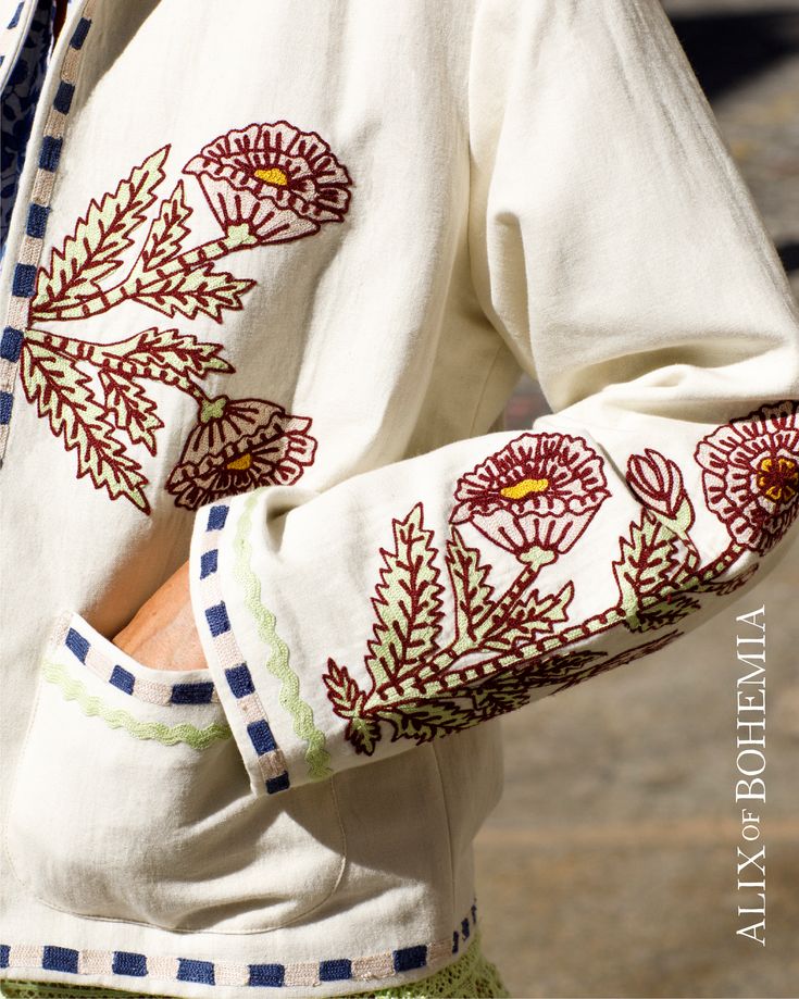 a close up of a person wearing a white shirt with red and green flowers on it