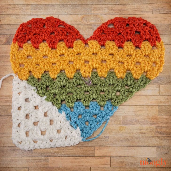 two crocheted hearts are sitting on the floor next to each other in different colors