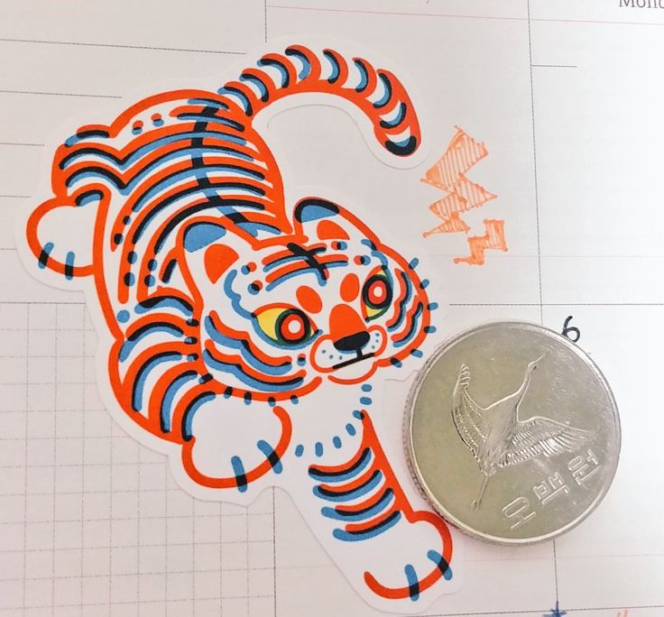 a coin sitting on top of a piece of paper next to a tiger sticker