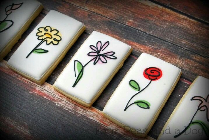 four decorated cookies sitting on top of a wooden table next to each other with flowers painted on them