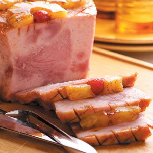 sliced ham and pineapples on a cutting board with two forks next to it