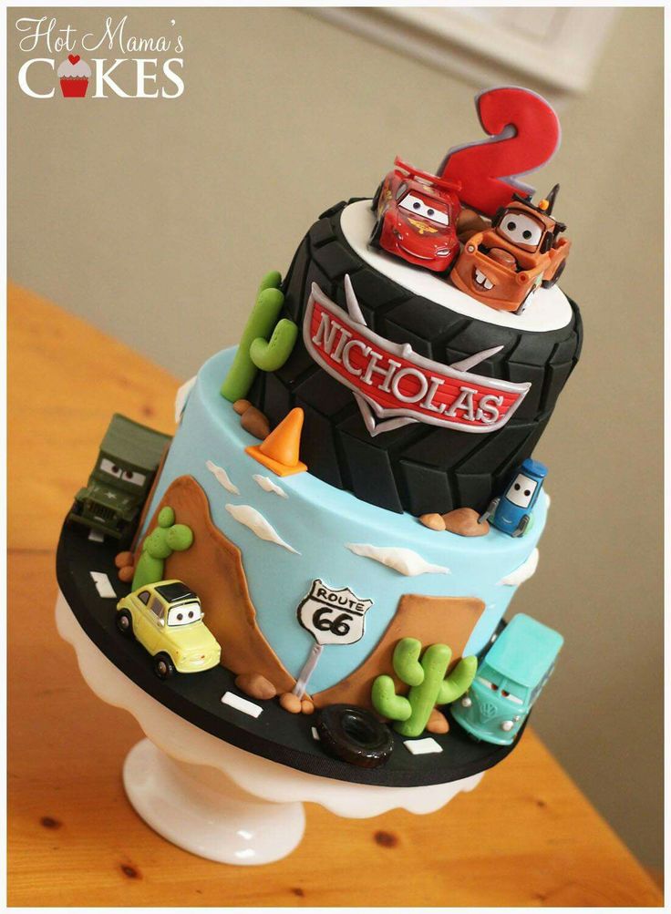 a birthday cake with cars and trucks on it's top tier is sitting on a table