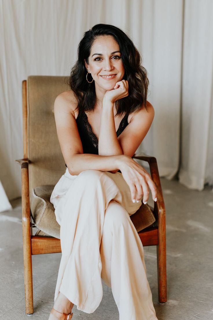 a woman sitting in a chair with her hand on her chin