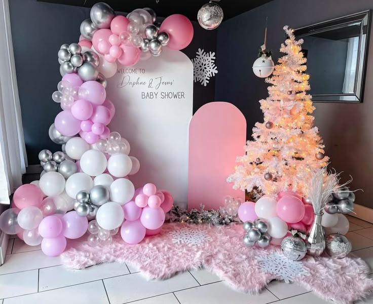 a pink and silver baby shower is decorated with balloons, snowflakes, and a christmas tree