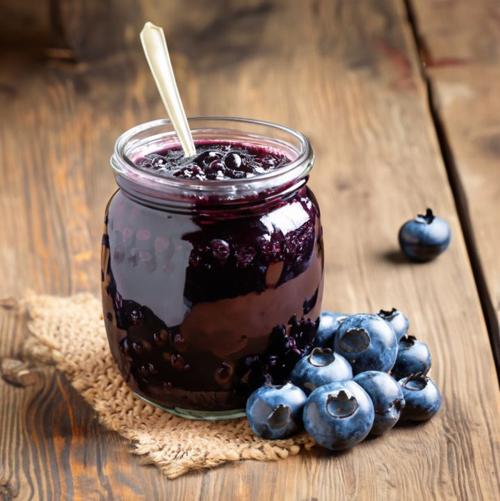 a glass jar filled with blueberries on top of a wooden table