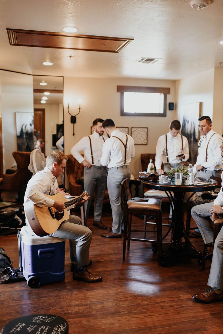 a group of men standing and sitting around a table with guitars in front of them