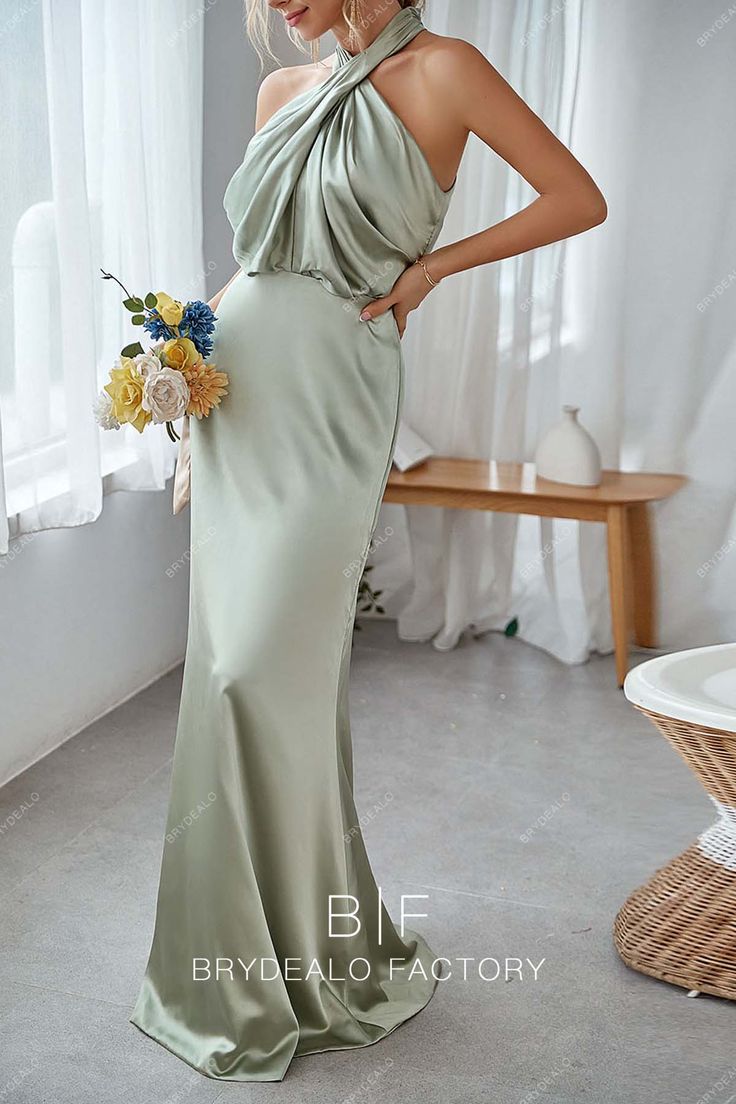 a woman in a long green dress standing next to a window with her hands on her hips