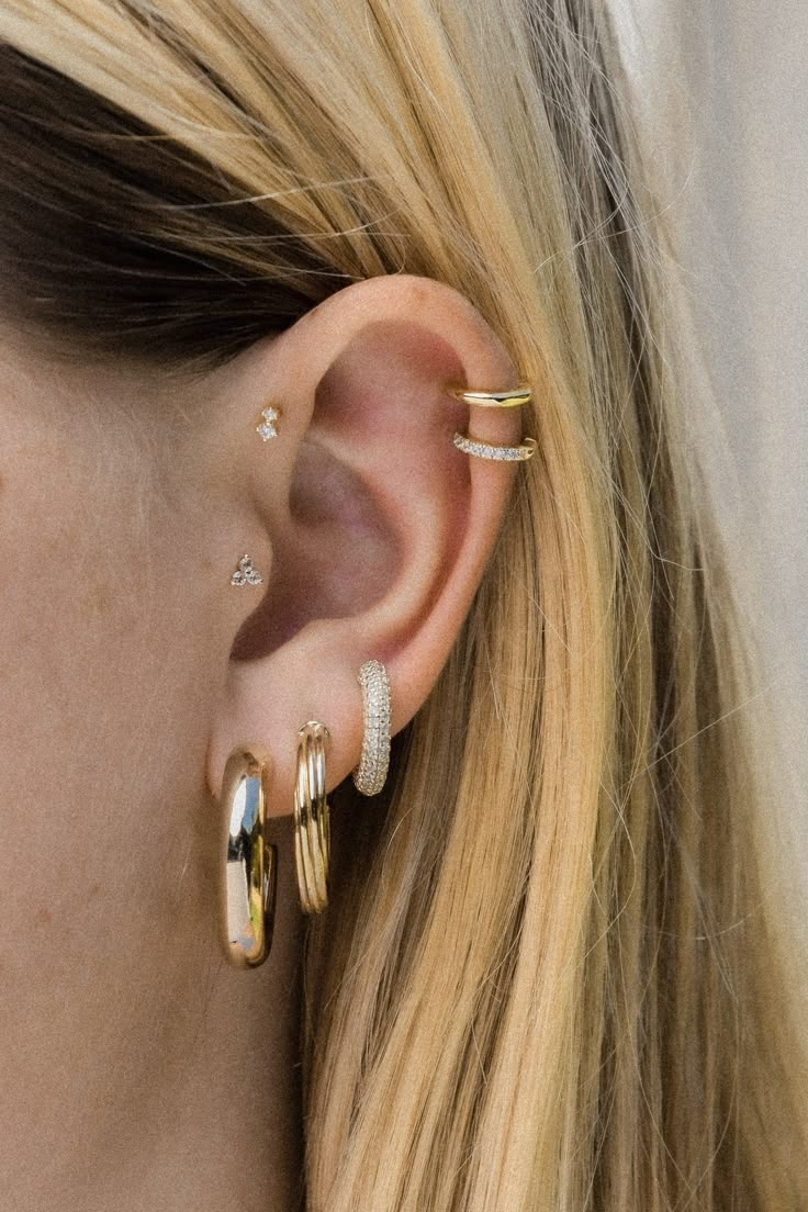 a close up of a person wearing two different types of ear piercings on their ears