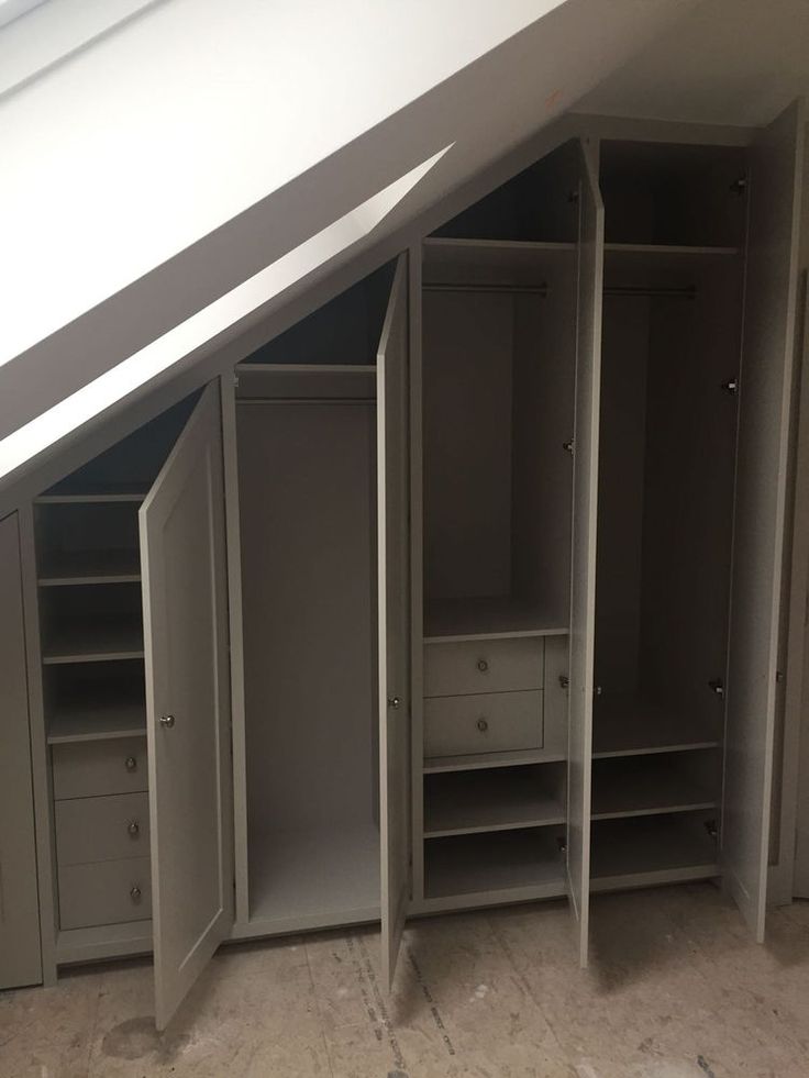 an attic bedroom with white closets and drawers