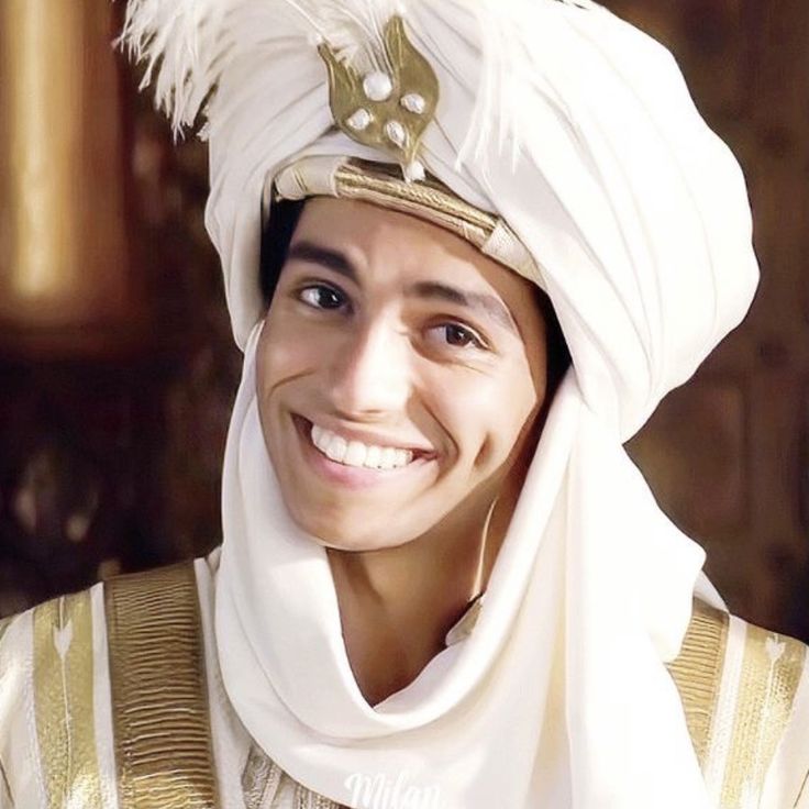 a man wearing a white turban smiles for the camera