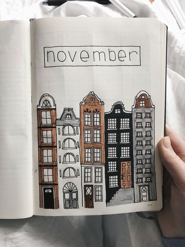 an open book with drawings of buildings and the words november written in black on it