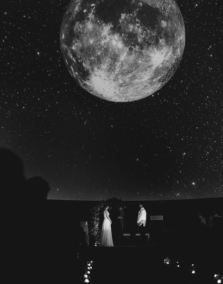 a black and white photo of a couple under the moon