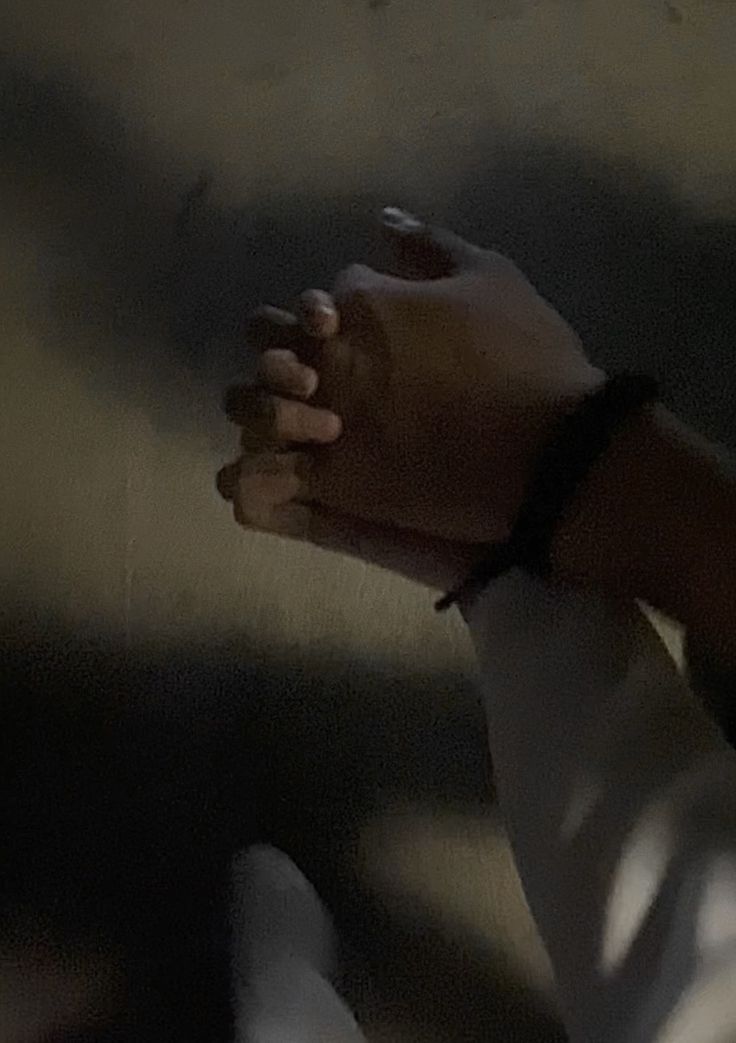 a person holding their hands together in the dark with shadows on the ground behind them