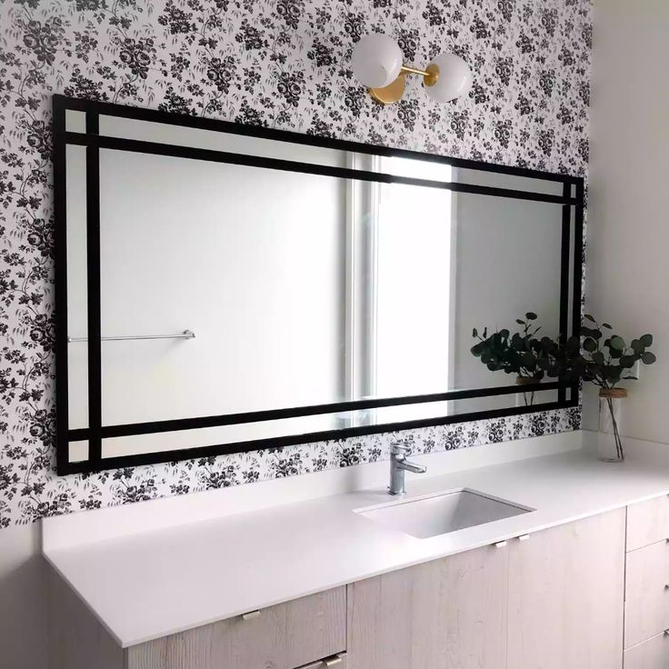 a bathroom with a sink, mirror and wallpapered walls in black and white