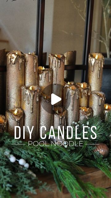 some candles sitting on top of a wooden table with pine cones and greenery around them